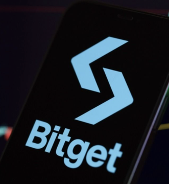 The image displays the Bitget cryptocurrency exchange logo on a smartphone screen, featuring the distinctive stylized "S" symbol in light blue alongside the "Bitget" branding. This visual ties directly to the announcement that Bitget is suspending crypto trading services for Japanese users by year's end due to regulatory compliance requirements.