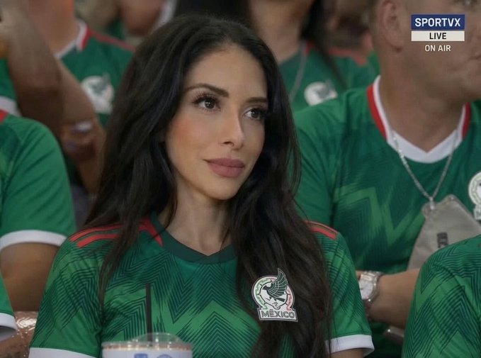 The image shows a woman with long dark hair wearing a Mexico national soccer team jersey, seated among other fans in green jerseys during a live broadcast on SPORTV (indicated by the "LIVE ON AIR" graphic in the top right corner). The visible "MÉXICO" team crest with the eagle emblem on her jersey aligns with the post's enthusiastic support for the Mexican national team, capturing her as a passionate fan ready to watch the match.