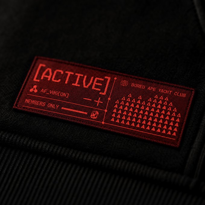 A close-up of a red embroidered label on black fabric reading '[ACTIVE]', 'AF_V06[ON]', 'MEMBERS ONLY', and 'BORED APE YACHT CLUB'.