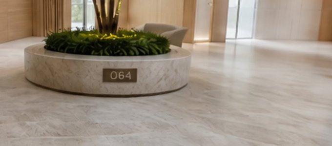 An interior view of a modern building lobby featuring a circular stone planter with greenery and a plaque reading "064".