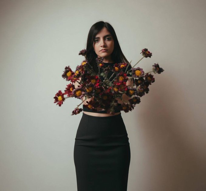 A young woman in a black crop top and skirt stands against a neutral wall, holding a large bouquet of dried red and yellow flowers that partially obscures her face. The somber, romantic aesthetic of the image visually echoes the wistful "Soft Ending" mood of the post, while the mention of "6/7 _ 8" suggests this is the sixth installment of a seven-part series.
