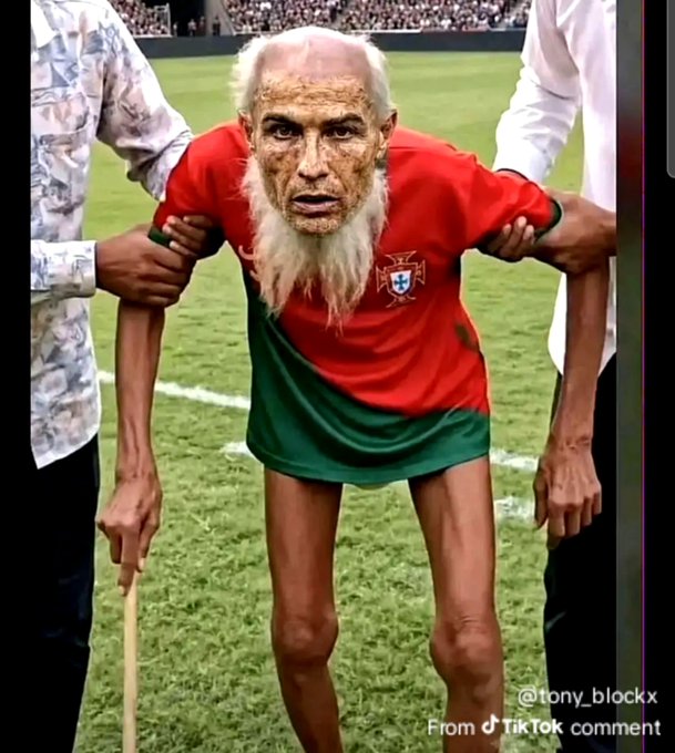 An elderly man with long white hair wearing a red and green Portugal jersey is supported by two people on a soccer field. The watermark reads "@tony_blockx From TikTok comment."