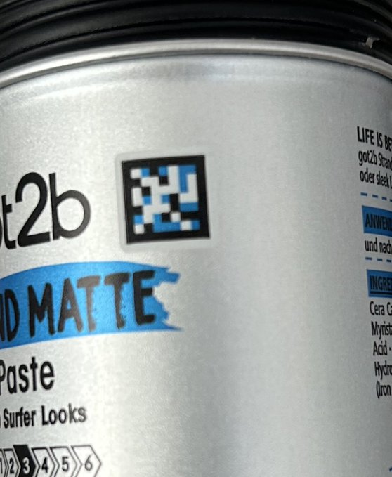 A close-up of a silver can of Got2b Mad Matt Styling Paste with a QR code sticker on the front.