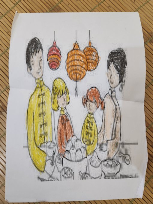 A child's colored pencil drawing on white paper showing four people in traditional Asian clothing standing around a bowl, with red and orange lanterns hanging above, displayed on a bamboo mat.