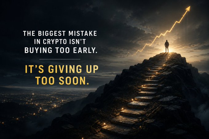 A lone figure stands atop a mountain of glowing steps beneath a rising golden arrow chart, paired with the text: "The biggest mistake in crypto isn't buying too early. It's giving up too soon." The imagery reinforces the post's message of perseverance, illustrating that those who climb steadily toward the peak are rewarded for their patience and consistency.