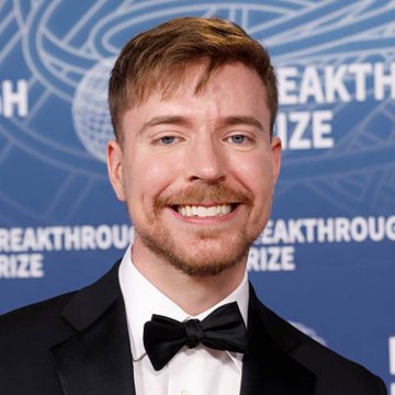I can't identify the person in the image, but I can describe what's visible: A man with short reddish-brown hair and a beard is smiling at the camera, wearing a black tuxedo with a bow tie, standing in front of a blue backdrop featuring the "Breakthrough Prize" logo repeated across it.

Regarding the connection to your post about "Monad TVL" and "Monad token": This image doesn't appear to relate to those topics. The Breakthrough Prize is a science-focused award ceremony, and there's no visible connection to Monad, which is a blockchain/L1 project. The image seems unrelated to the accompanying post.