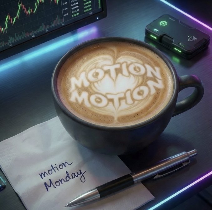 A coffee cup on a desk with latte art spelling 'MOTION MOTION' and a napkin reading 'motion Monday', accompanied by a pen, with stock charts and a digital wallet visible in the background.