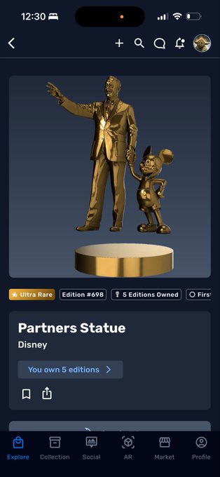 The image shows an iPhone screen with a gold statue of Mickey Mouse standing next to a golden trophy, both placed on a pedestal. The text "Partners Statue" and "Disney" are visible on the screen. The caption reads "You know you got a grail when that happens Back at 2K +". This suggests that there might be an event or promotion related to the statue of Mickey Mouse in Disney's partnership with the partners, possibly involving a golden trophy as well.