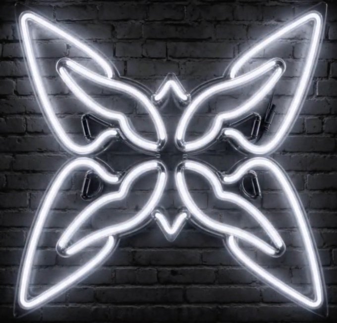 A bright white neon sign shaped like a butterfly with geometric wings mounted on a dark brick wall.