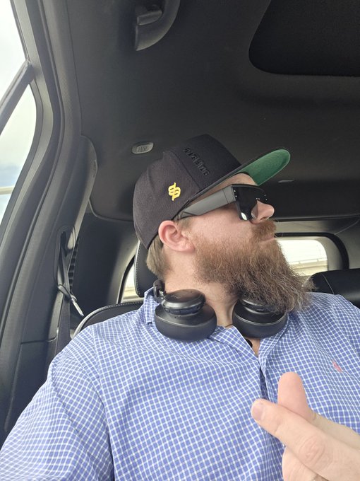 The image features a man wearing sunglasses, a hat with a logo, and headphones while sitting inside a car. The man appears to be making a funny face or gesture as part of a humorous caption posted online. The caption reads "I look a little incognito flying today... but that @solflare pops... IYKYK if I start talking about IBRL just know I am trying to get the attention of @eden_".