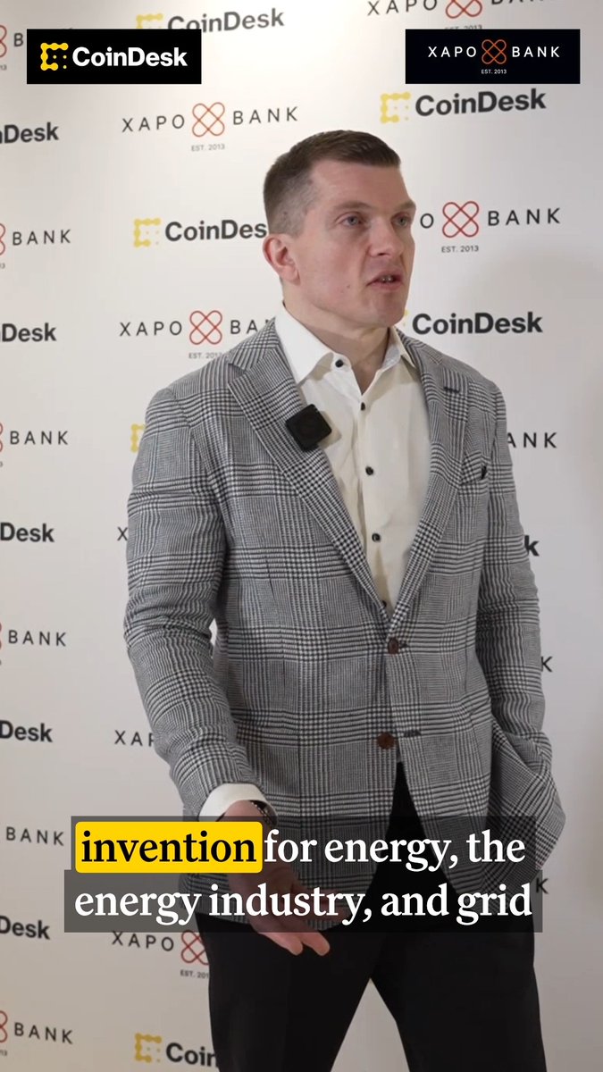 A man in a gray plaid blazer being interviewed at a CoinDesk and Xapo Bank event, with caption text reading 'invention for energy, the energy industry, and grid'.