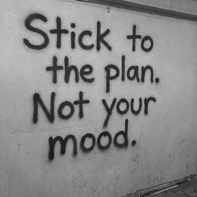 Black spray-painted graffiti on a light-colored wall that reads 'Stick to the plan. Not your mood.'