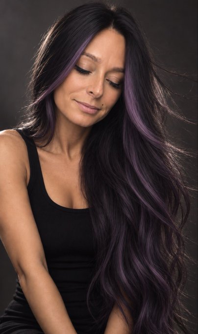A studio portrait features a woman with long dark hair featuring purple highlights, wearing a black tank top with her eyes closed against a dark gray background.