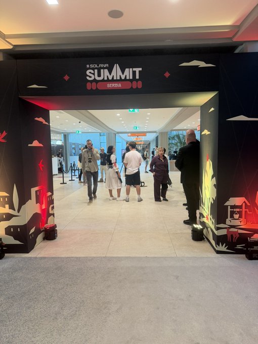 Entrance to the Solana Summit Serdia event, featuring a black archway with decorative panels of Asian-inspired buildings and clouds, with attendees walking through into the convention hall.