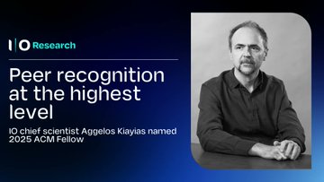 The image features a man sitting at a desk with his hands resting on his lap. The background of the image is blue, which contrasts with the man's black shirt. There are two texts displayed in the image that read "IO Research" and "Peer Recognition at the highest level".