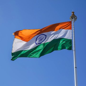 The Indian flag waves against a clear blue sky, symbolizing the country whose Financial Intelligence Unit (FIU) has issued non-compliance notices to 15 crypto platforms for breaching anti-money laundering (AML) regulations.