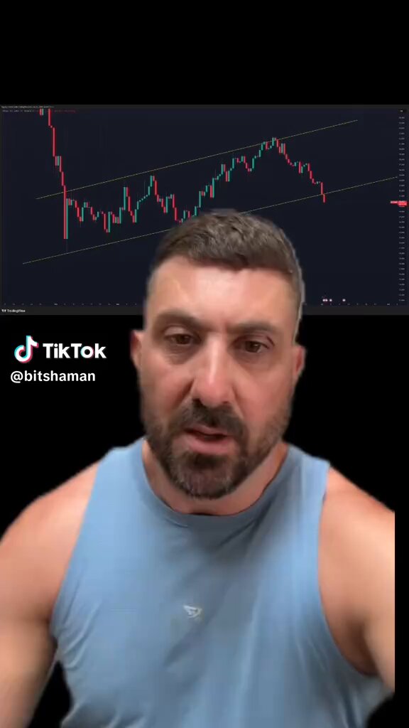 The image shows a man wearing a blue tank top with his chin resting on his fist, appearing to be in deep thought or contemplation about Bitcoin. The title of the image reads "Bitcoin has finally broken out of the bear flag", which references the Bitcoin cryptocurrency rising from its previous bearish position in the market. This suggests that Bitcoin is experiencing significant growth and the man might be analyzing this development as a financial decision, possibly contemplating whether to invest or hold onto his Bitcoins.