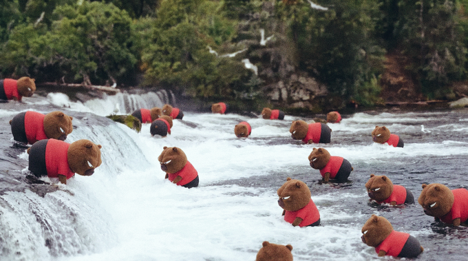A large group of cartoon bears wearing red shirts stand in a river in what appears to be a whimsical scene.