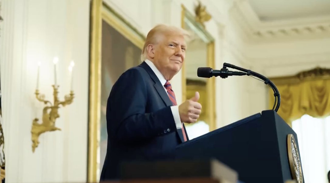 Donald Trump at a podium giving a thumbs-up in an ornate room with gold décor.