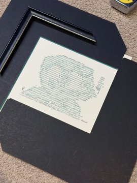 A black folder lies open on a carpeted floor, displaying a handwritten page of text on light green paper, with a black pen resting on top of the folder.