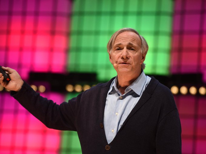 Ray Dalio, the billionaire investor, is shown speaking on stage with a clicker in hand, likely delivering his remarks about central banks not owning significant Bitcoin due to government preferences for private, controlled transactions.