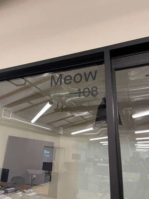 A glass office door is labeled with "Meow 108" in dark lettering, showing the exposed ceiling and office interior behind it. The "$MEOW" ticker referenced in the post playfully aligns with the company name "Meow" displayed on this conference room door, reinforcing the feline branding central to the cryptocurrency's identity.