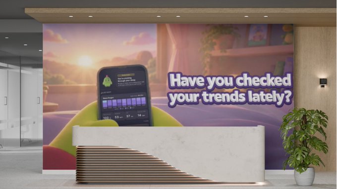 A modern office lobby reception area featuring a large wall mural of a phone displaying a financial chart with the text 'Have you checked your trends lately?'
