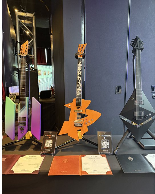 Three custom-built guitars designed by @thisistimronan stand on display at the Blockchain Futurist Conference in Toronto, each themed around a major cryptocurrency: a green/purple Bitcoin guitar, an orange "THUNDER" Ethereum guitar, and a black geometric Solana guitar, with corresponding QR-coded placards and certificates arranged on the table below.
