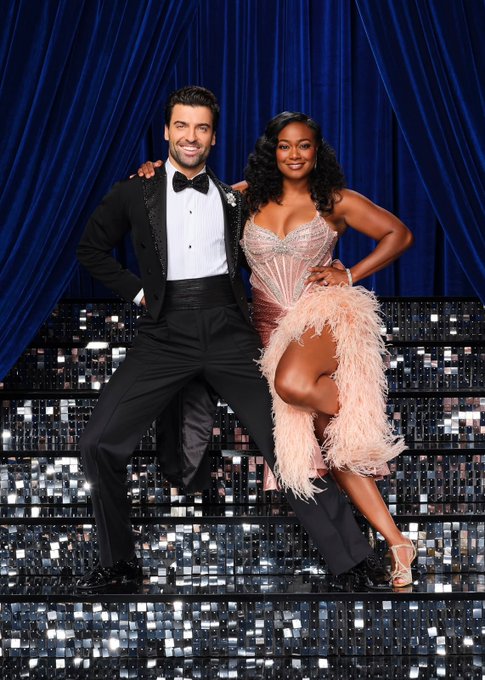 The image features Dancing With The Stars contestant Tatyana Ali posing with her dance partner in glamorous ballroom attire on a sequined staircase stage. This visual connects to the Polymarket prediction regarding her 43% chance of elimination in Season 35, Week 3 of the competition.