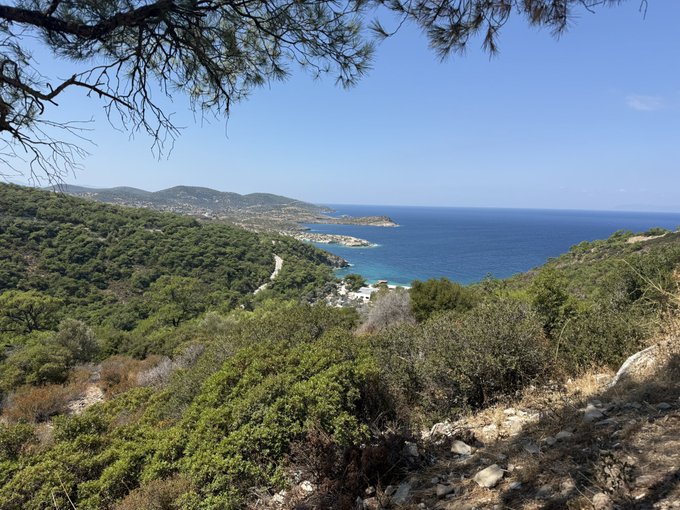 A scenic coastal view of a tranquil Mediterranean bay surrounded by lush green hillsides, with a small town nestled along the shoreline under a clear blue sky. The image reflects the poster's peaceful mindset, contrasting their reflection on the week's busy crypto activity with a moment of relaxation and appreciation for nature's beauty.