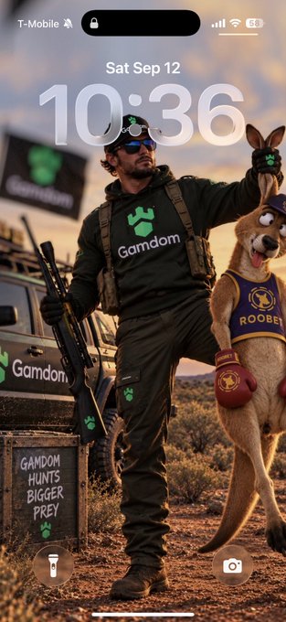 The lock screen displays a soldier figure wearing "Gamdom" branded gear alongside a kangaroo in boxing gloves with "ROOBET" on its jersey, with a small chalkboard reading "GAMDOM HUNTS BIGGER PREY." The time shows 10:36 on Sat Sep 12. The image aligns with the post's playful military/gambling rivalry narrative, using the "Gamdom hunts bigger prey" slogan and kangaroo boxing imagery as motivation to "battle" rival casinos.