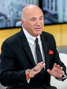Kevin O'Leary, the entrepreneur and investor, is shown in a black suit with a red pocket square speaking animatedly in what appears to be a television studio setting, illustrating the post about his bullish stance on crypto as he announces he's buying new positions for the next market cycle.