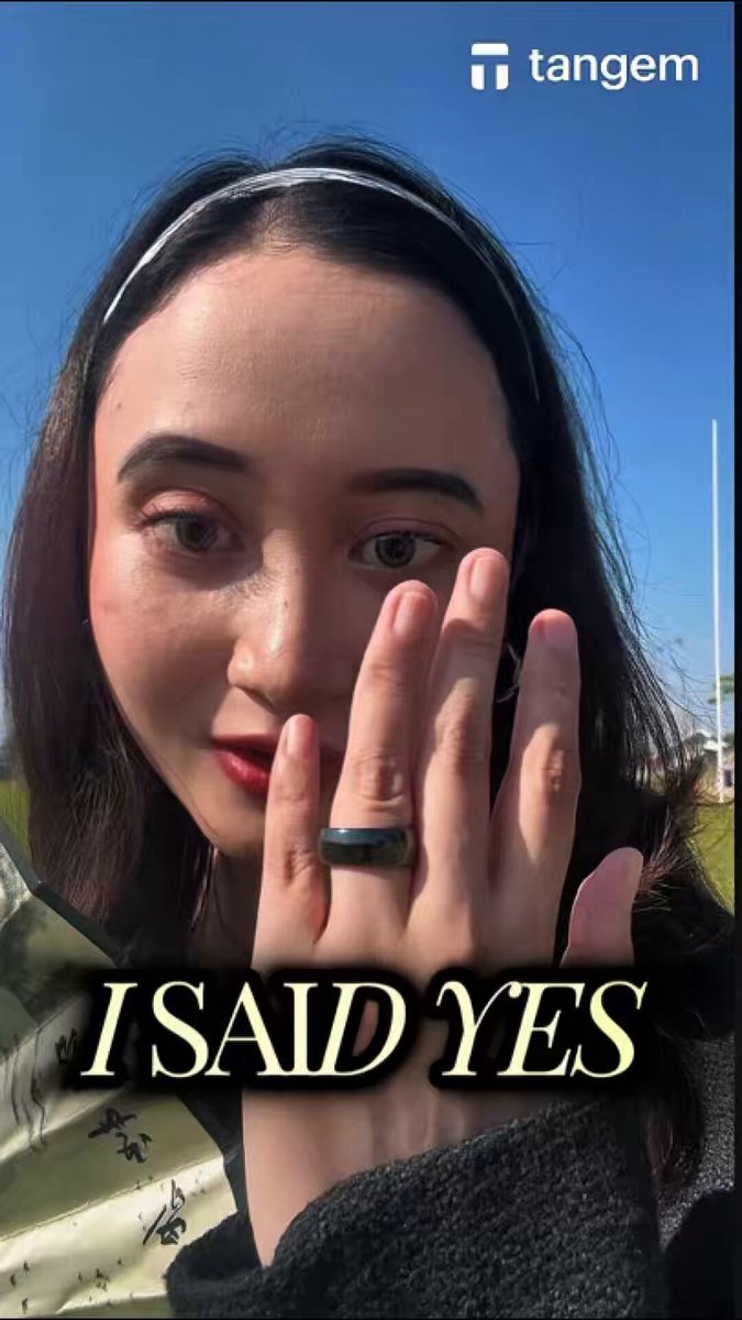 The image features a woman with long brown hair, wearing a black jacket, who has her hand raised up to her face as if she's about to say something or make a gesture. The caption of the image reads "I SAID YES" which is written in yellow text at the bottom right corner of the photo.