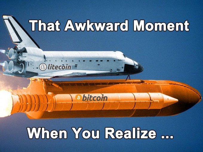 The image features a space shuttle flying through the air, with an orange Bitcoin logo on its side. Below the space shuttle, there's text that reads "That Awkward Moment When You Realize... @LitecoinVM mainnet?". The combination of the space shuttle and Bitcoin logos creates a humorous juxtaposition between space travel and cryptocurrency.