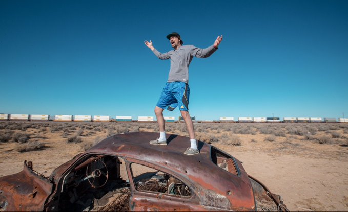 The image features a man standing on top of an old, rusted car that appears to be abandoned or decommissioned. The man has his arms outstretched as if he's celebrating something or expressing joy. In the background, there are several train cars visible, suggesting that this scene might have taken place in a location where trains once operated. The image also contains text that reads "Credit Card coming to @metalpaysme @LOAN_Protocol Send it to the heavens!!!!". This message seems to be related to the man's situation or the abandoned car, possibly indicating an unexpected event or discovery.