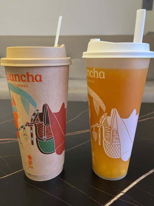 Two colorful disposable cups from "Nancha" bubble tea, one featuring a panda design in green and red tones, and the other with a gradient orange-yellow design.