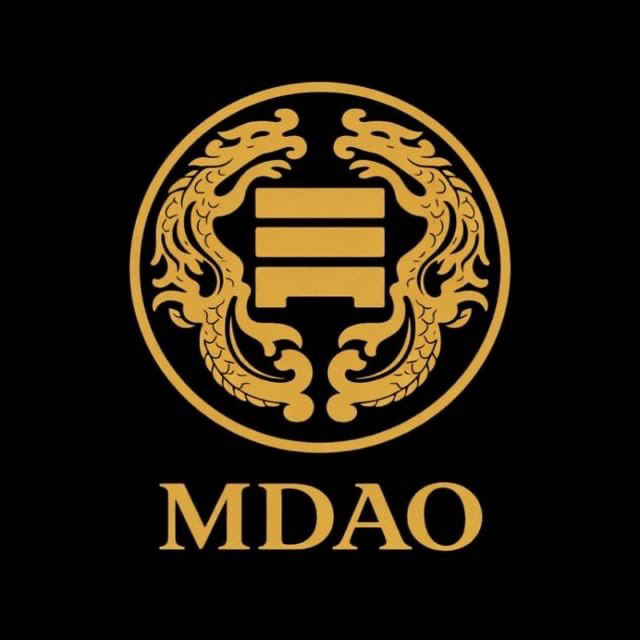 A gold circular logo featuring two dragons flanking a stylized symbol on a black background, with the text "MDAO" displayed below.
