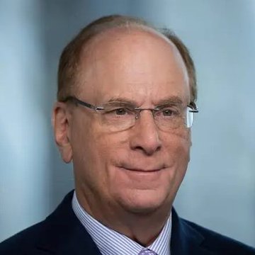 A professional headshot of an older man with glasses, wearing a dark suit jacket and a light blue striped shirt against a blue gradient background.