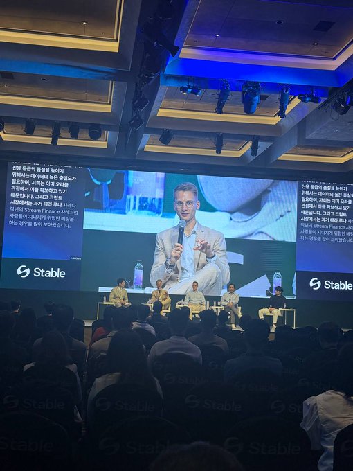 A conference panel with the 'Stable' logo, where a speaker is shown on the large screen giving a presentation with Korean subtitles, while the panel sits on stage.