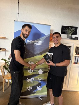 Two men shake hands indoors in front of a 'Superteam HALON' banner depicting mountains, with one holding an NFT trophy; NFT artwork is visible on the left wall.