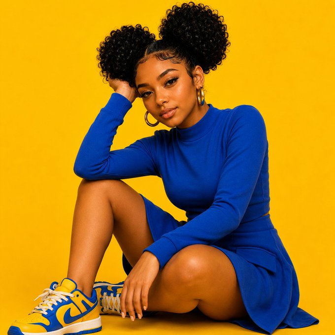 A young woman with double afro puffs sits against a yellow background wearing a royal blue long-sleeved dress and matching yellow and blue Nike sneakers.