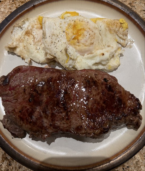A plate of food featuring a cooked steak alongside three fried eggs seasoned with black pepper.
