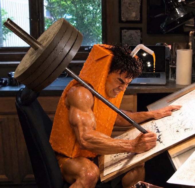 An AI-generated or surreal image of a muscular man with a barbell for a head, wearing an orange cheese wedge costume and intensely drawing on paper at a drafting table.