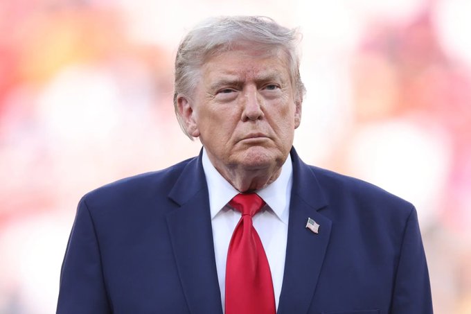 A close-up of Donald Trump in a suit and red tie, this image visually represents the subject of the accompanying post discussing his involvement in passing the CLARITY Act. The small US flag pin on his lapel signifies his role as a political figure.