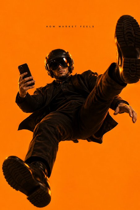 A stylized photo of a man wearing a motorcycle helmet and goggles, lying on his back against an orange background while looking at a smartphone, with the caption 'HOW MARKET FEELS'.