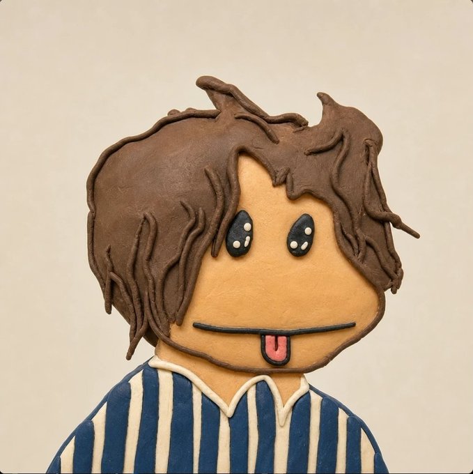 A decorated cookie or cake shaped like a cartoon character with shaggy brown hair, large shiny eyes, a small tongue sticking out, and wearing a blue and white striped shirt.