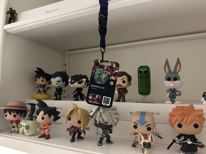 A collection of Funko Pop figurines displayed on shelves, with an anime-style ID badge on a lanyard hanging in the center reading 'KOWSKY.eth'.
