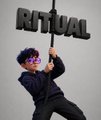 A small image of a person wearing sunglasses and a black jacket standing under the 3D word 'RITUAL' against a plain white background.