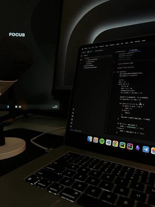 A laptop displaying code in VS Code is shown next to a monitor with the text "FOCUS." The image evokes the focused, dedicated work often required for success, complementing a celebratory post about GN Winners and the importance of teamwork.