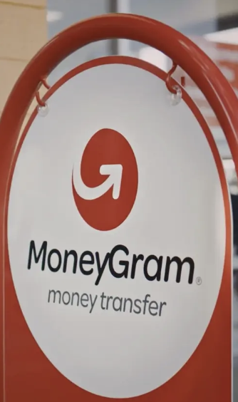 A red and white MoneyGram sign reads "MoneyGram money transfer" alongside the company's logo. The image represents the company's brand as it announces the expansion of its MoneyGram Ramps cash-to-crypto service to the Solana blockchain.